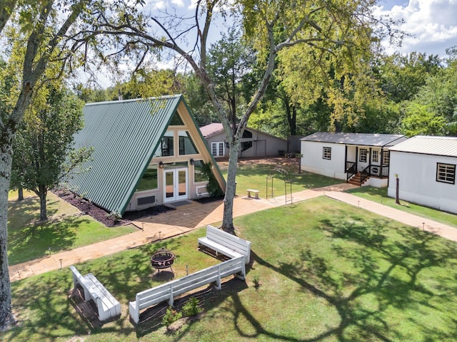 back of property with french doors, an outdoor fire pit, and a lawn