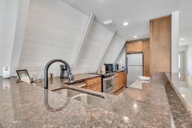 kitchen with stainless steel appliances, sink, and dark stone countertops