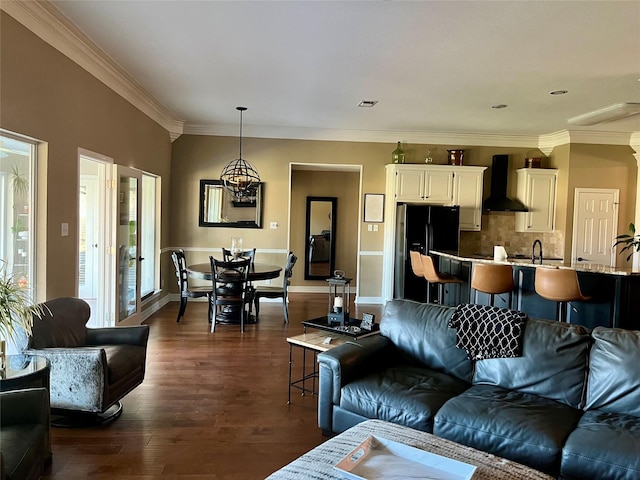 living room with a notable chandelier, ornamental molding, and dark wood-type flooring