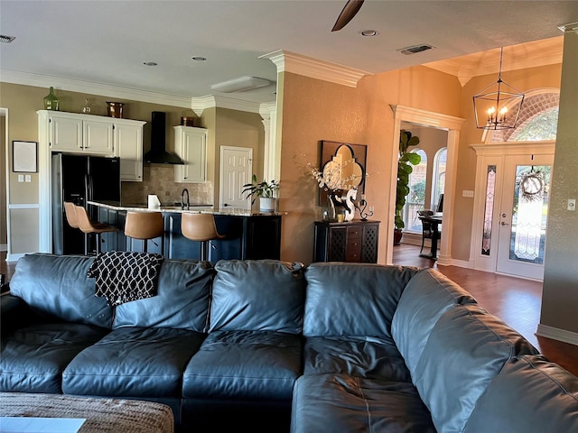 living room featuring sink, a chandelier, dark hardwood / wood-style floors, and ornamental molding