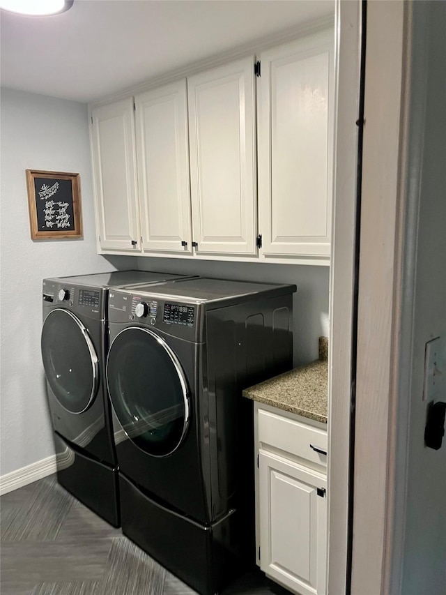 clothes washing area featuring cabinets and washer and clothes dryer