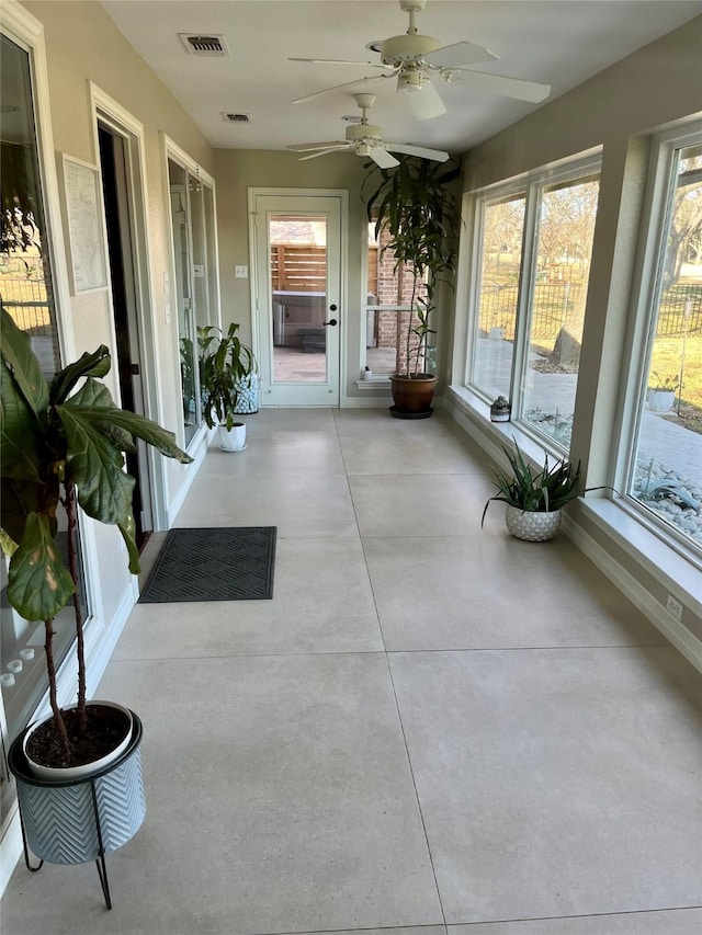 unfurnished sunroom featuring ceiling fan and a healthy amount of sunlight