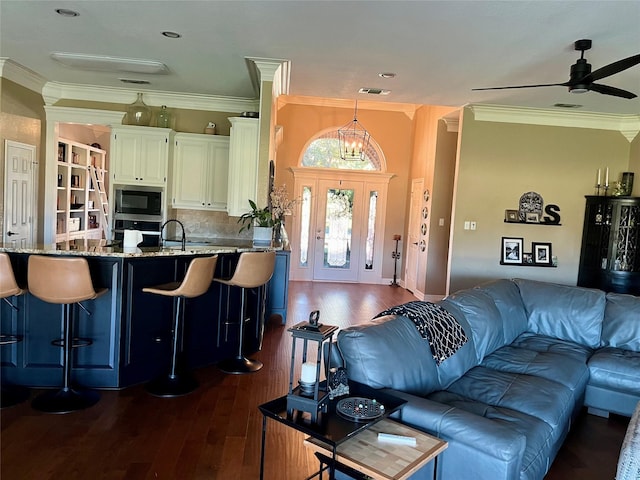 living room with ceiling fan with notable chandelier, ornamental molding, dark hardwood / wood-style flooring, and sink