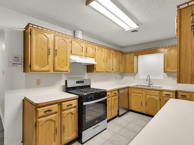 kitchen featuring stainless steel appliances, light tile patterned flooring, sink, and a textured ceiling