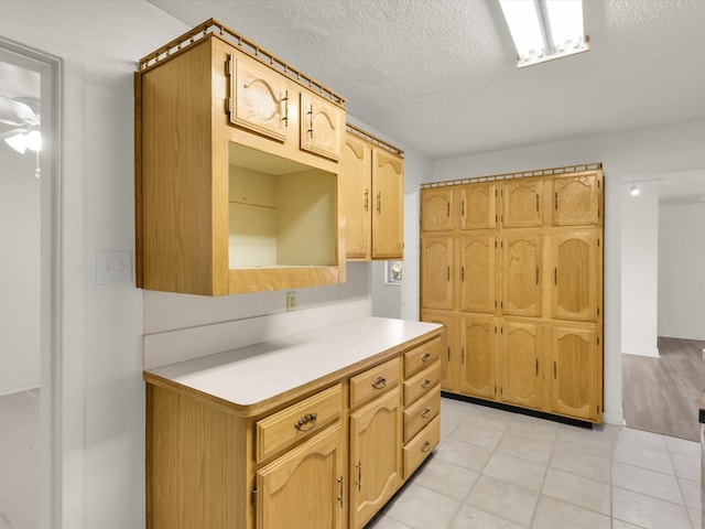 kitchen with light brown cabinets, light tile patterned floors, and a textured ceiling