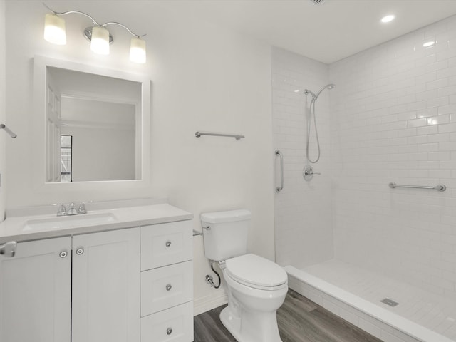 bathroom featuring tiled shower, wood-type flooring, toilet, and vanity