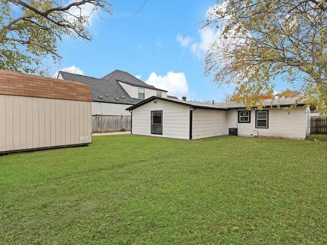 rear view of house with a lawn, central air condition unit, and a storage unit