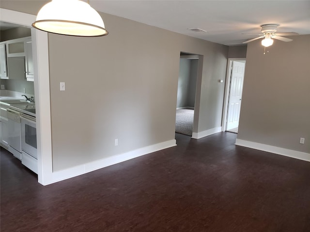 empty room featuring ceiling fan, sink, and dark wood-type flooring