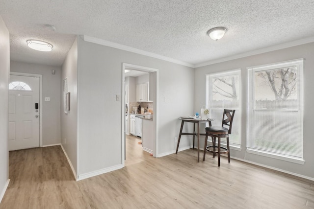 foyer entrance with light hardwood / wood-style floors, crown molding, and a healthy amount of sunlight