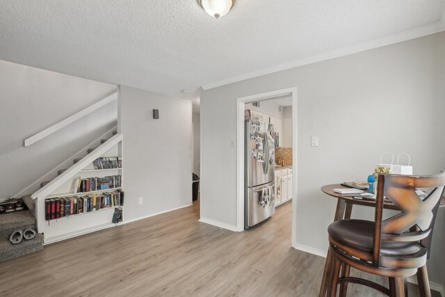 interior space featuring ornamental molding, a textured ceiling, and light wood-type flooring