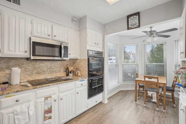 kitchen featuring white cabinets, light stone countertops, and black appliances