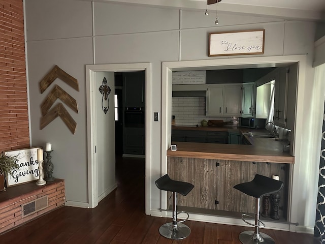 interior space featuring black oven, dark hardwood / wood-style flooring, lofted ceiling, and sink