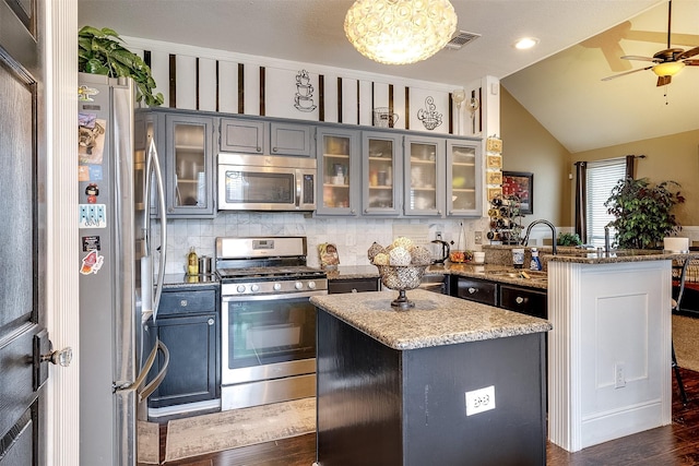 kitchen featuring stainless steel appliances, a center island, sink, and light stone countertops