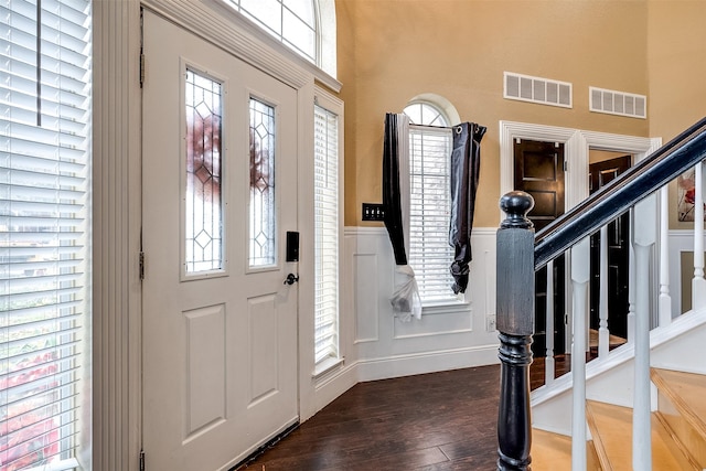 foyer entrance featuring dark wood-type flooring and a towering ceiling