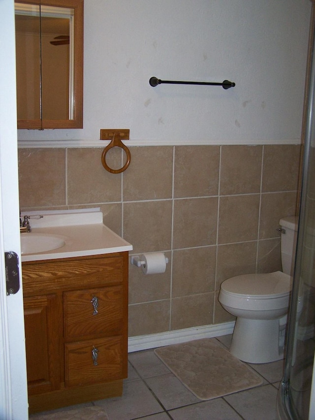 bathroom featuring tile patterned flooring, vanity, tile walls, and toilet