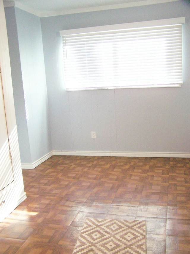 unfurnished room featuring ornamental molding and dark parquet flooring