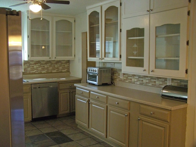 kitchen with appliances with stainless steel finishes, dark tile patterned flooring, ceiling fan, and decorative backsplash