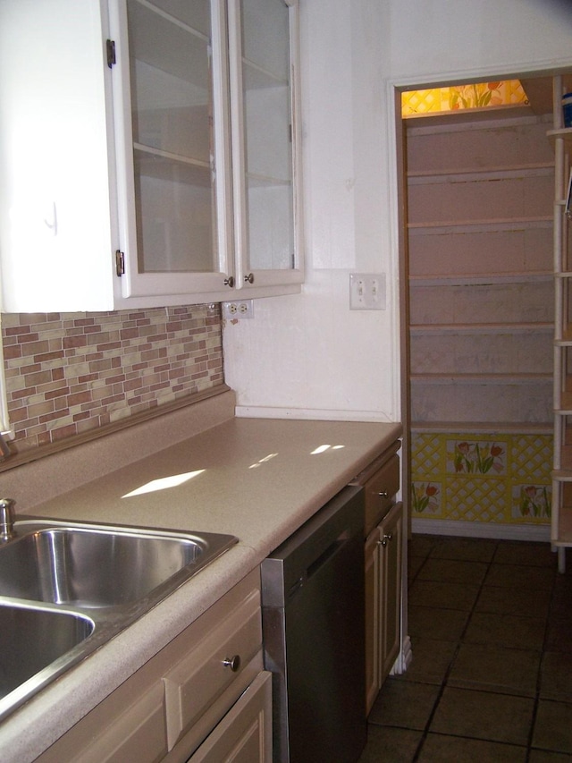 kitchen with sink, white cabinetry, dark tile patterned flooring, dishwasher, and decorative backsplash