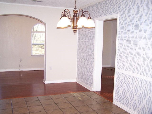 unfurnished room featuring dark wood-type flooring, ornamental molding, an inviting chandelier, and a textured ceiling