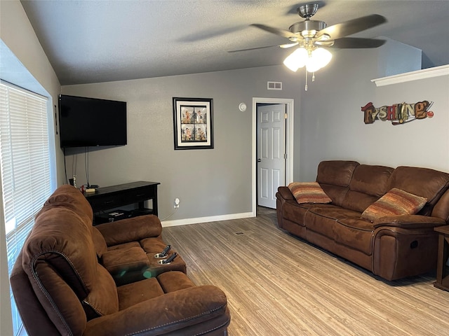 living room featuring ceiling fan, lofted ceiling, a textured ceiling, and light hardwood / wood-style flooring