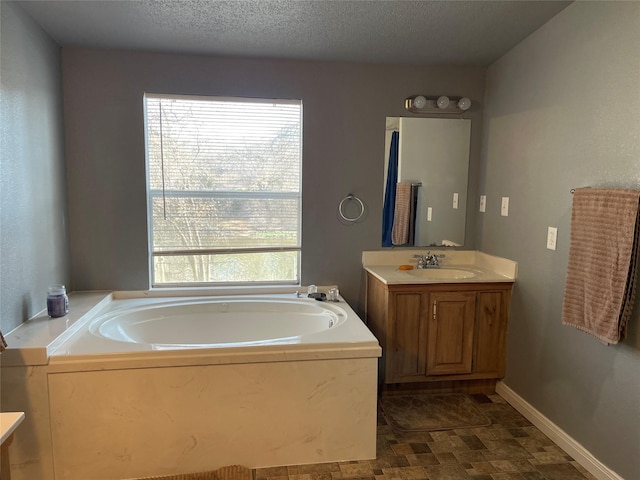 bathroom featuring a bathtub, vanity, a textured ceiling, and a wealth of natural light