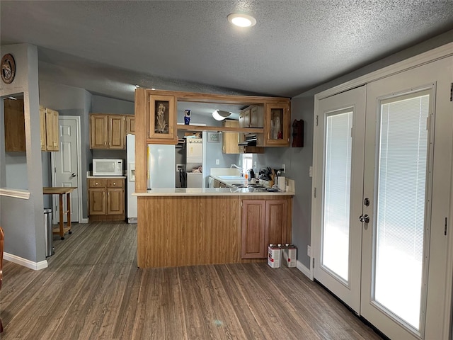 kitchen featuring kitchen peninsula, french doors, white appliances, vaulted ceiling, and dark wood-type flooring