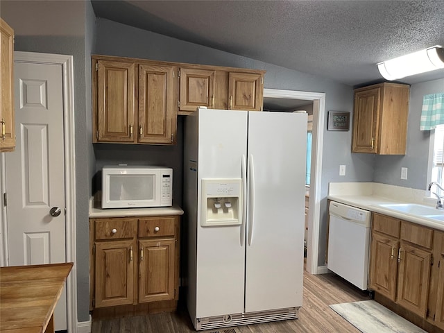 kitchen featuring a textured ceiling, white appliances, sink, light hardwood / wood-style flooring, and lofted ceiling