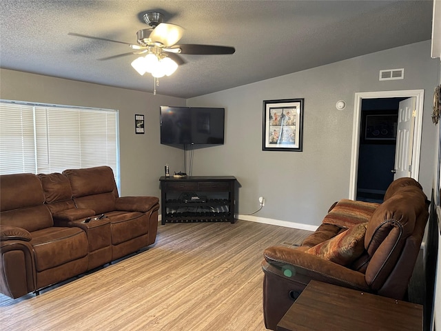 living room featuring a textured ceiling, ceiling fan, light hardwood / wood-style flooring, and vaulted ceiling