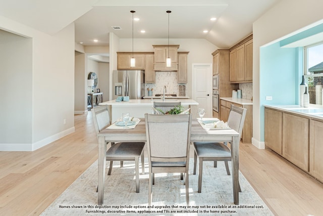 dining room featuring light hardwood / wood-style flooring, vaulted ceiling, and sink