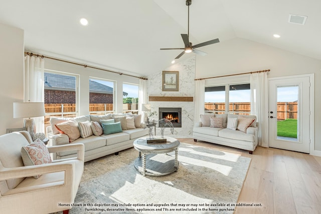 living room featuring high vaulted ceiling, a high end fireplace, light hardwood / wood-style floors, and ceiling fan