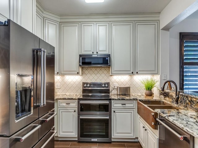 kitchen with sink, decorative backsplash, stone counters, and appliances with stainless steel finishes