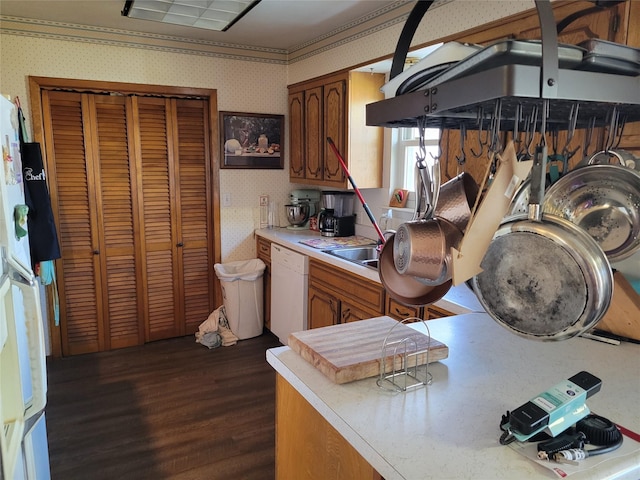 kitchen with dark wood-type flooring, white appliances, ornamental molding, and sink