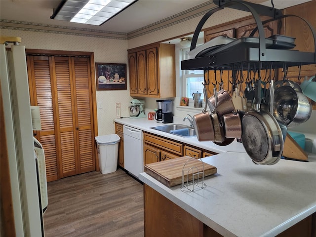 kitchen featuring white dishwasher, hardwood / wood-style flooring, kitchen peninsula, and sink