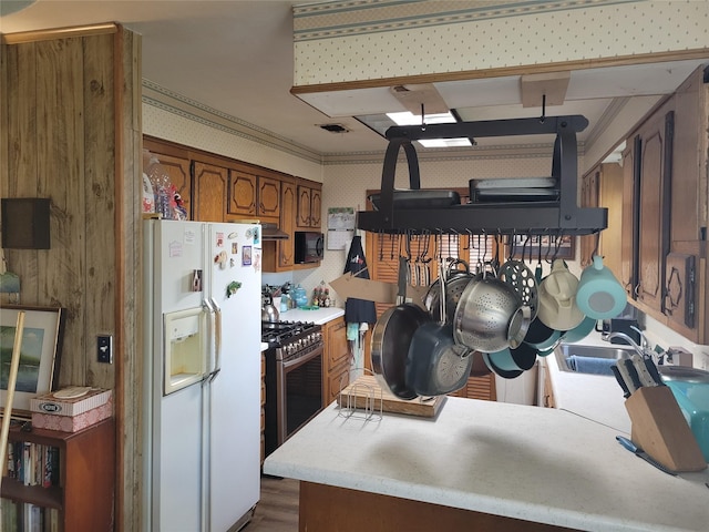 kitchen with sink, white refrigerator with ice dispenser, gas stove, and kitchen peninsula