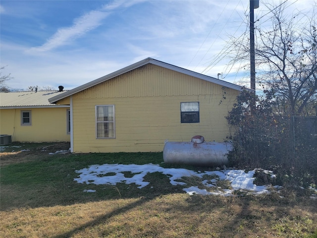 view of property exterior with central AC unit and a lawn