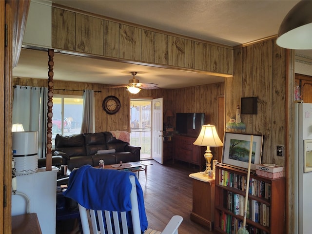 living room with dark hardwood / wood-style floors, ceiling fan, and wood walls