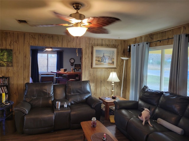 living room featuring ceiling fan and wooden walls