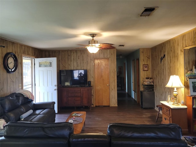 living room featuring dark hardwood / wood-style floors, ceiling fan, and wood walls