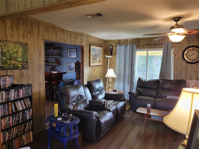 living room with dark wood-type flooring, wooden walls, and ceiling fan