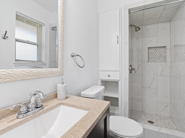 bathroom with toilet, vanity, and tiled shower