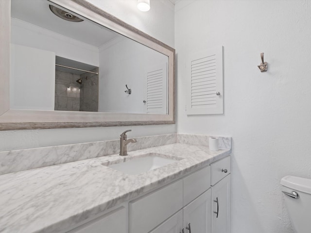 bathroom with tiled shower, vanity, ornamental molding, and toilet