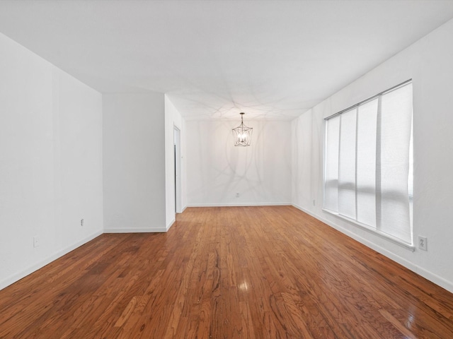 unfurnished room with hardwood / wood-style flooring and an inviting chandelier