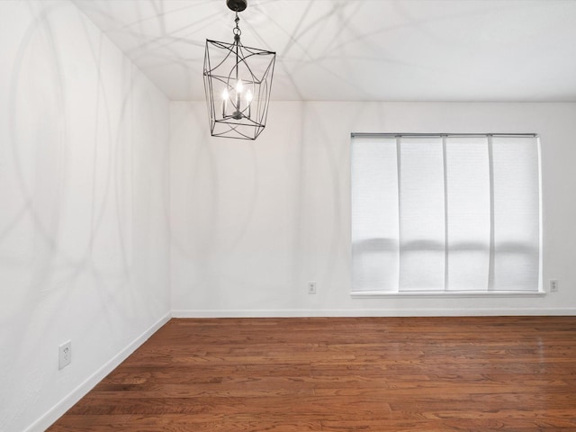 unfurnished room featuring a notable chandelier and dark hardwood / wood-style floors