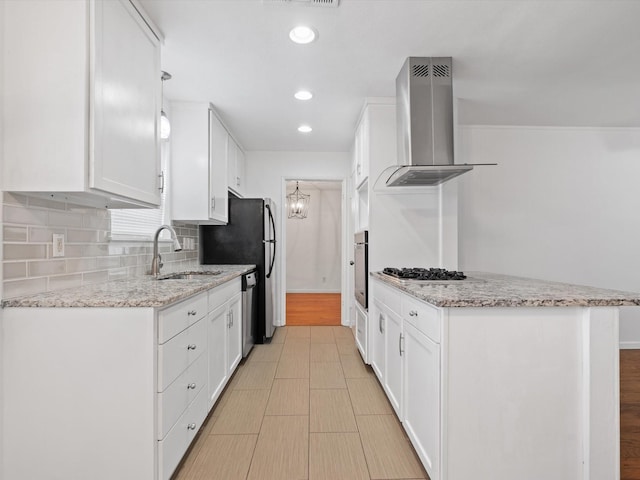 kitchen with white cabinetry, sink, wall chimney exhaust hood, light stone counters, and appliances with stainless steel finishes