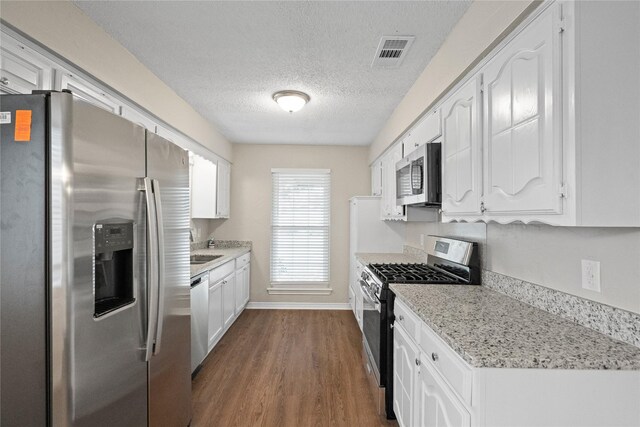 kitchen featuring dark wood-type flooring, light stone countertops, a textured ceiling, appliances with stainless steel finishes, and white cabinetry