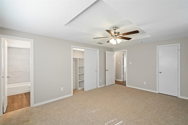 unfurnished bedroom featuring carpet flooring, ensuite bathroom, ceiling fan, and a textured ceiling