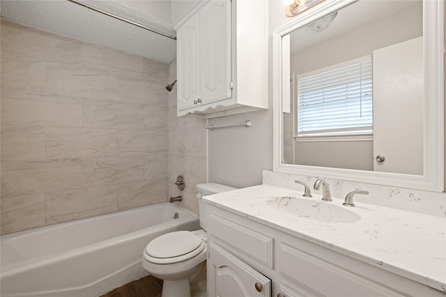 full bathroom with a textured ceiling, vanity, toilet, and tiled shower / bath