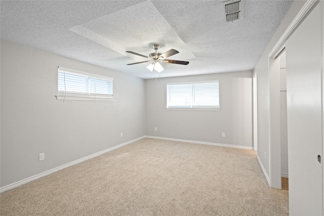 empty room featuring light carpet, a textured ceiling, plenty of natural light, and ceiling fan