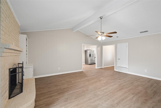 unfurnished living room with ceiling fan, a brick fireplace, lofted ceiling with beams, crown molding, and hardwood / wood-style floors