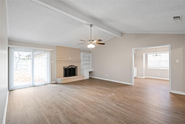 unfurnished living room featuring ceiling fan with notable chandelier, a brick fireplace, vaulted ceiling with beams, a textured ceiling, and wood-type flooring